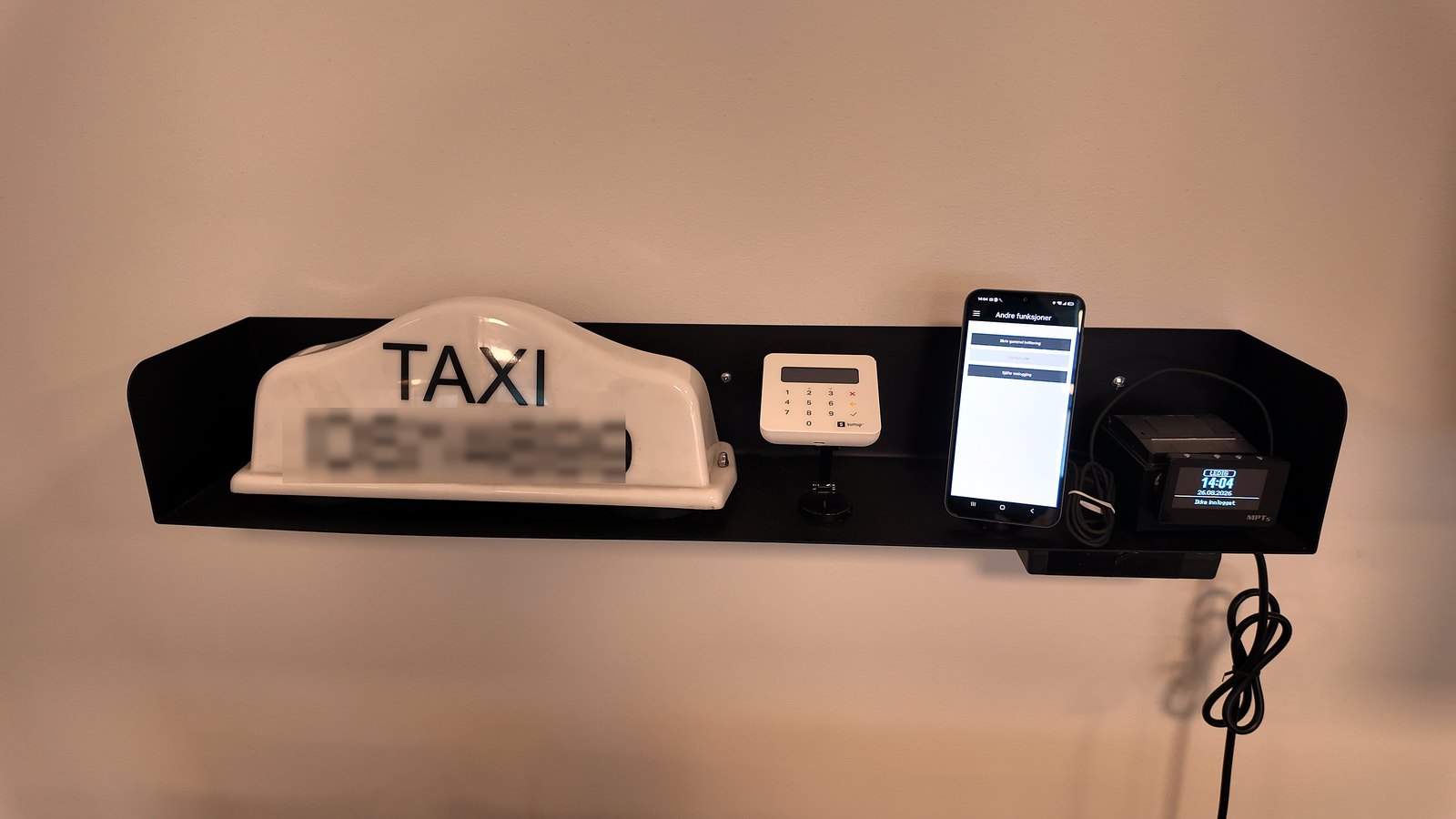 Opplæringsveggen på kontoret, med taklampe, taksameter og kortterminal